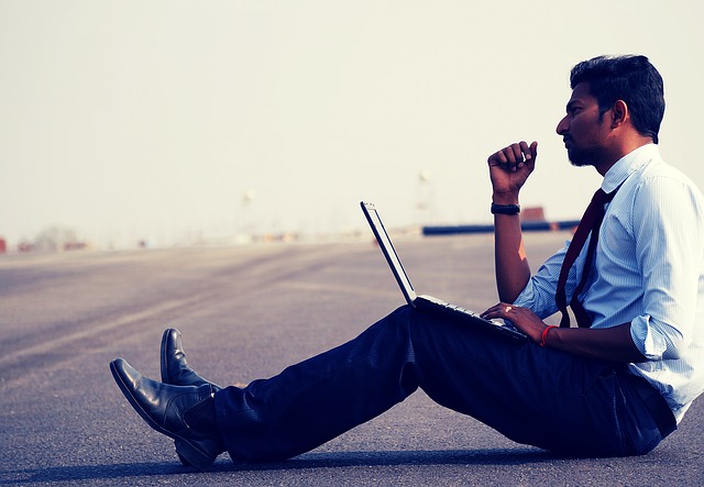 muž sedící s notebookem na silnici